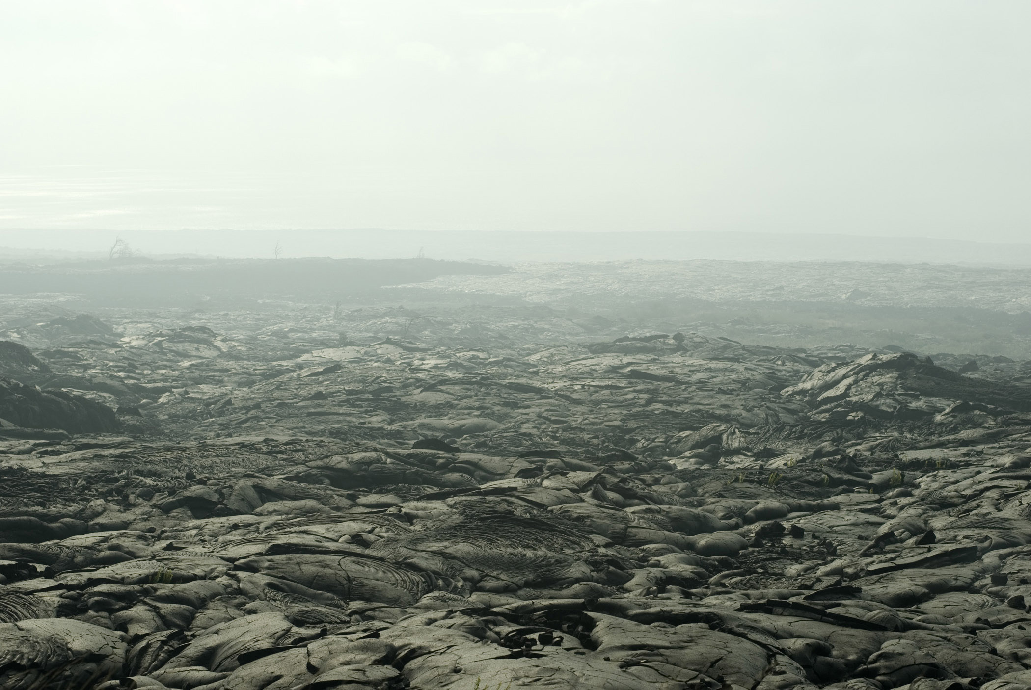 an image of Smoke at Black Surface Textured Lava Field in Extensive Panoramic View, Located in Hawaii.