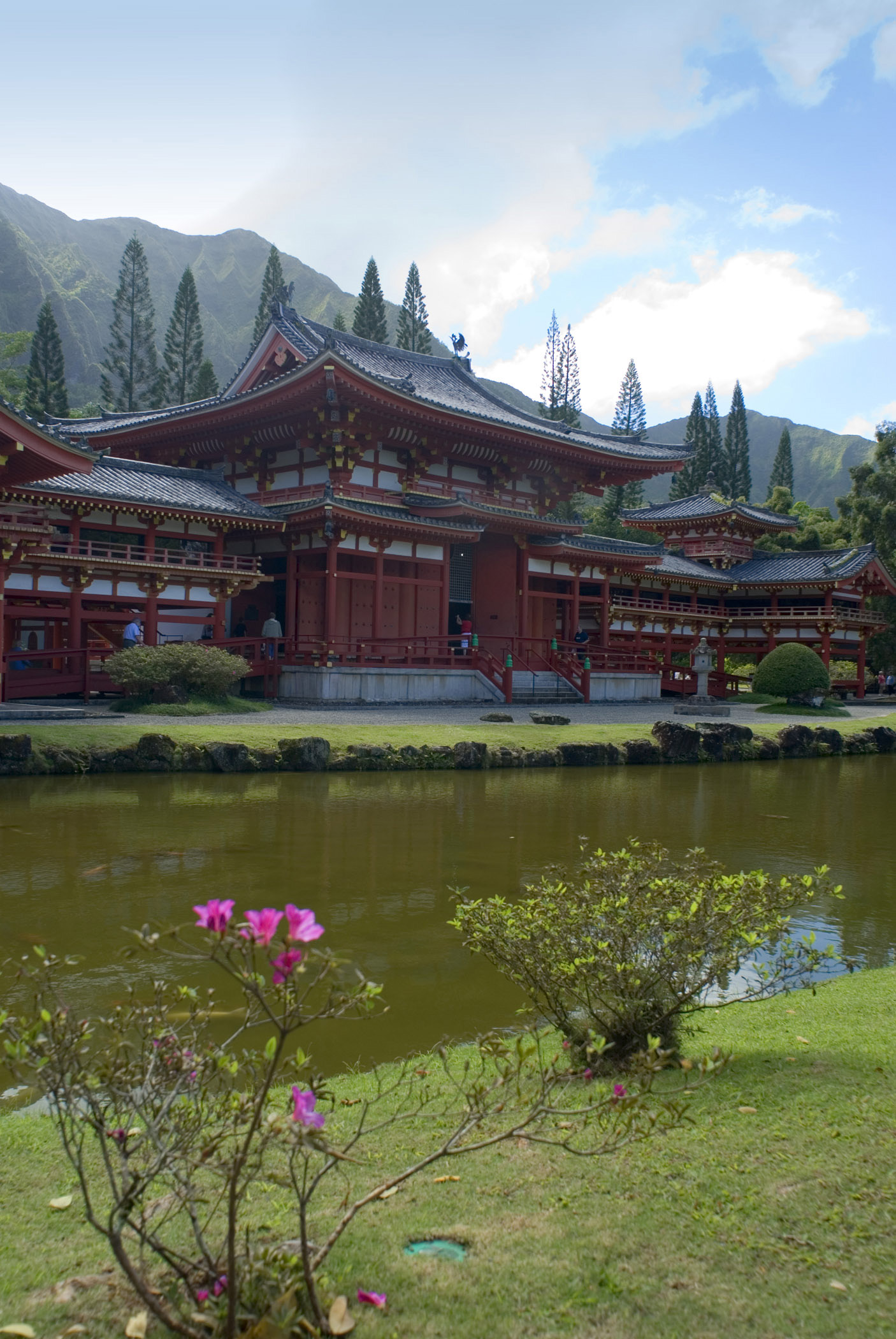 an image of Byodo-In Buddhist Temple, a replica Japanese temple for worship in the lush Hawaiian landscape, viewed across a tranquil pond