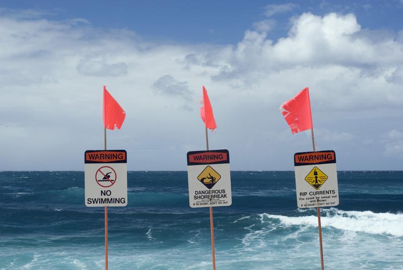 Three No Swimming Warning Signage with Small Flags at the Blue Water Beach.