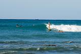 Woman surfing on Waikiki Beach riding in on a wave with other surfers paddling around her, Oahu Island, Hawaii, USA