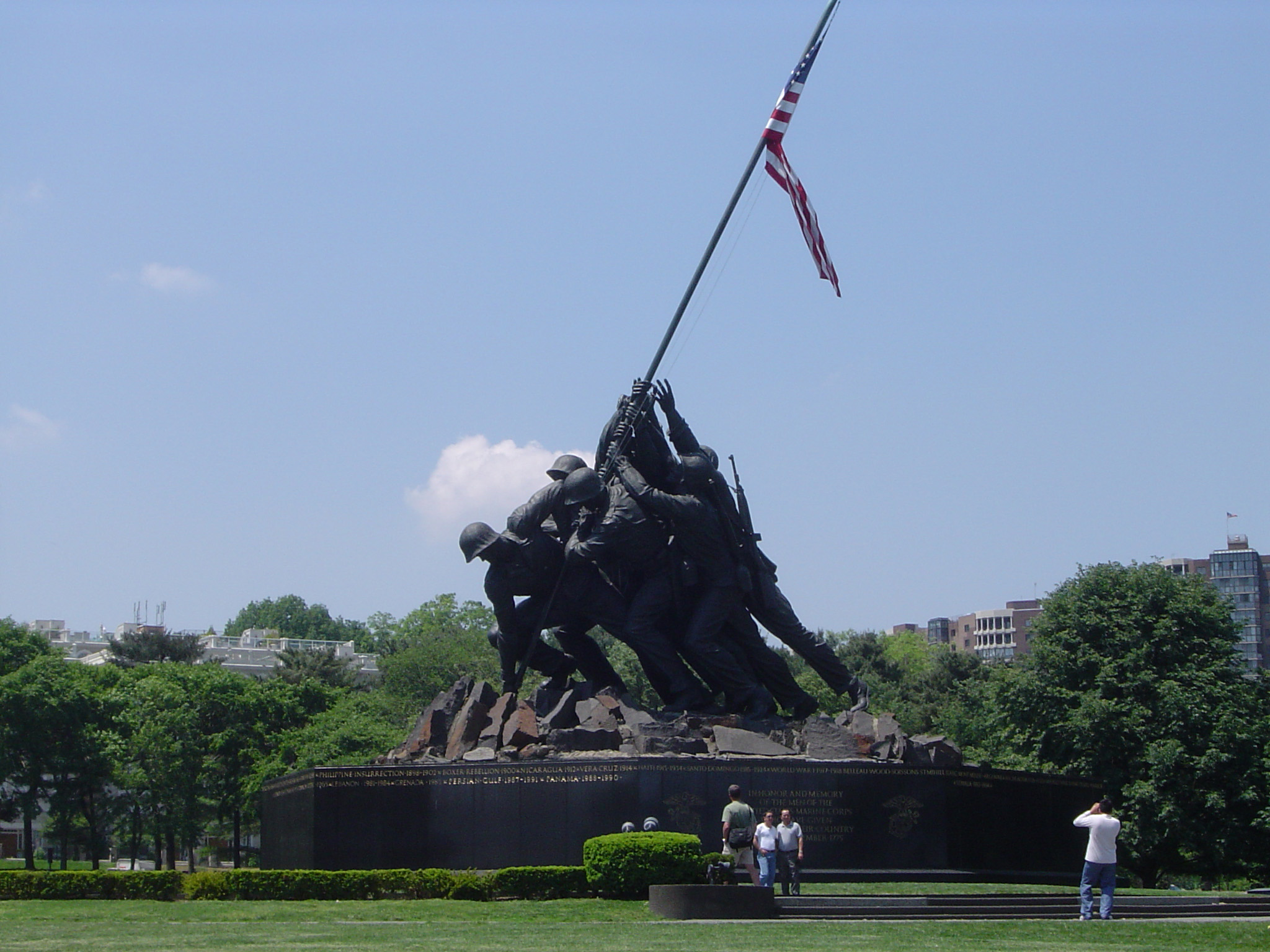 an image of Historic Black War Memorial Statue of Marine Corps with American Flag on Huge Platform. Isolated on Light Blue Gray Sky Background.