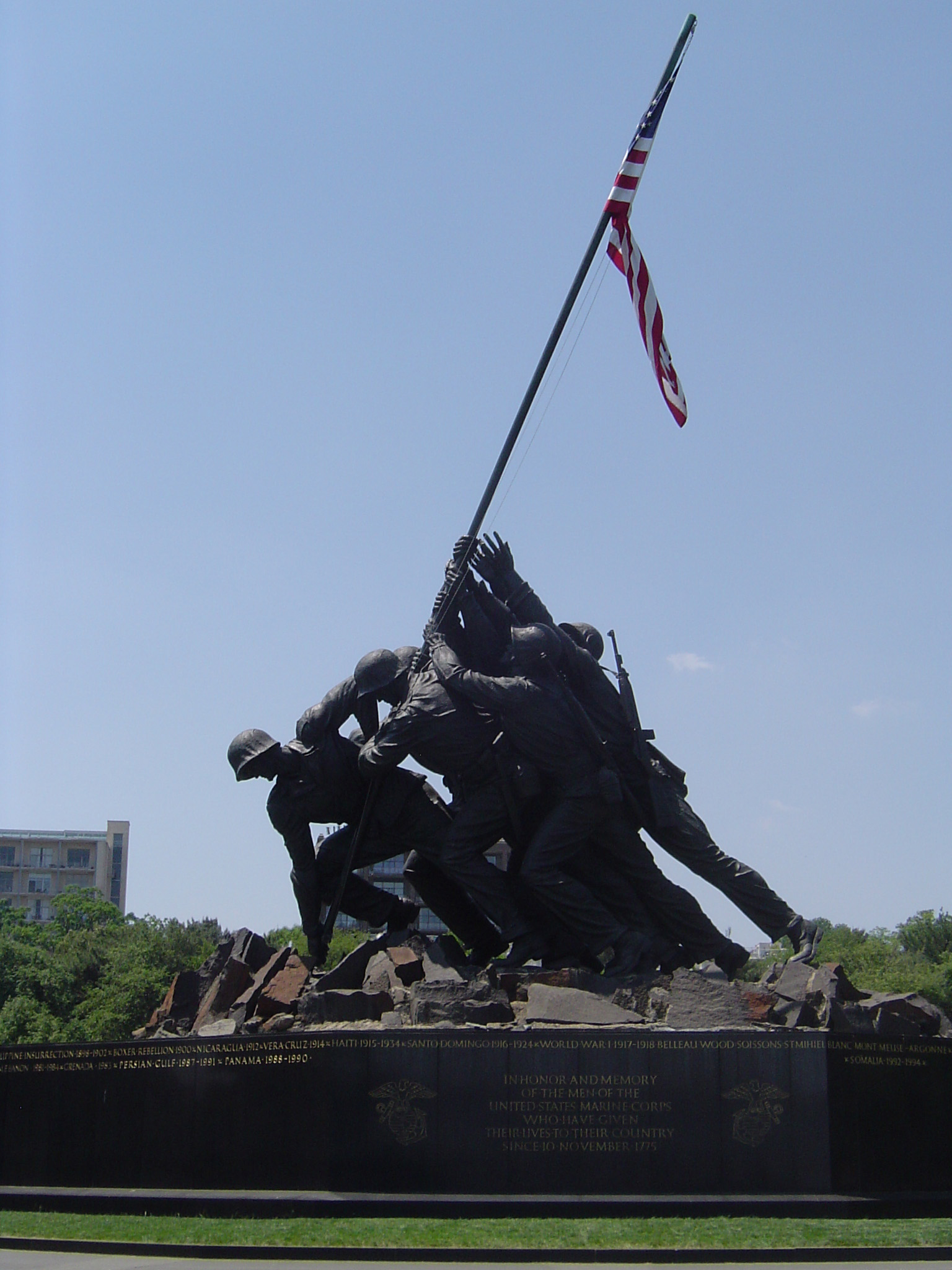 an image of Old Vintage Marine Corps War Memorial Statue Holding American Flag. Isolated on Light Blue Gray Sky Background.