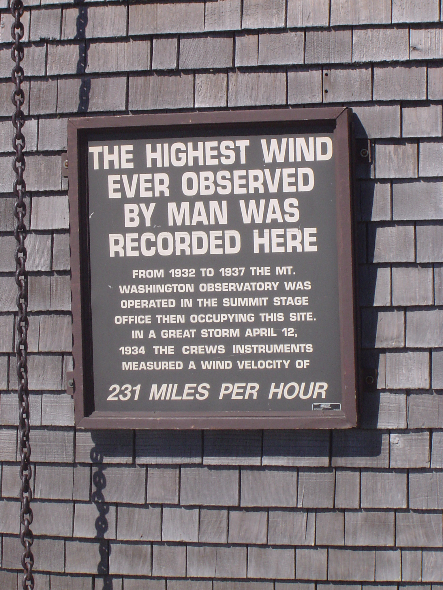 an image of Windiest place on earth with a metal plaque on Mount Washington recording the highest winds of 231 miles per hour ever recorded by man