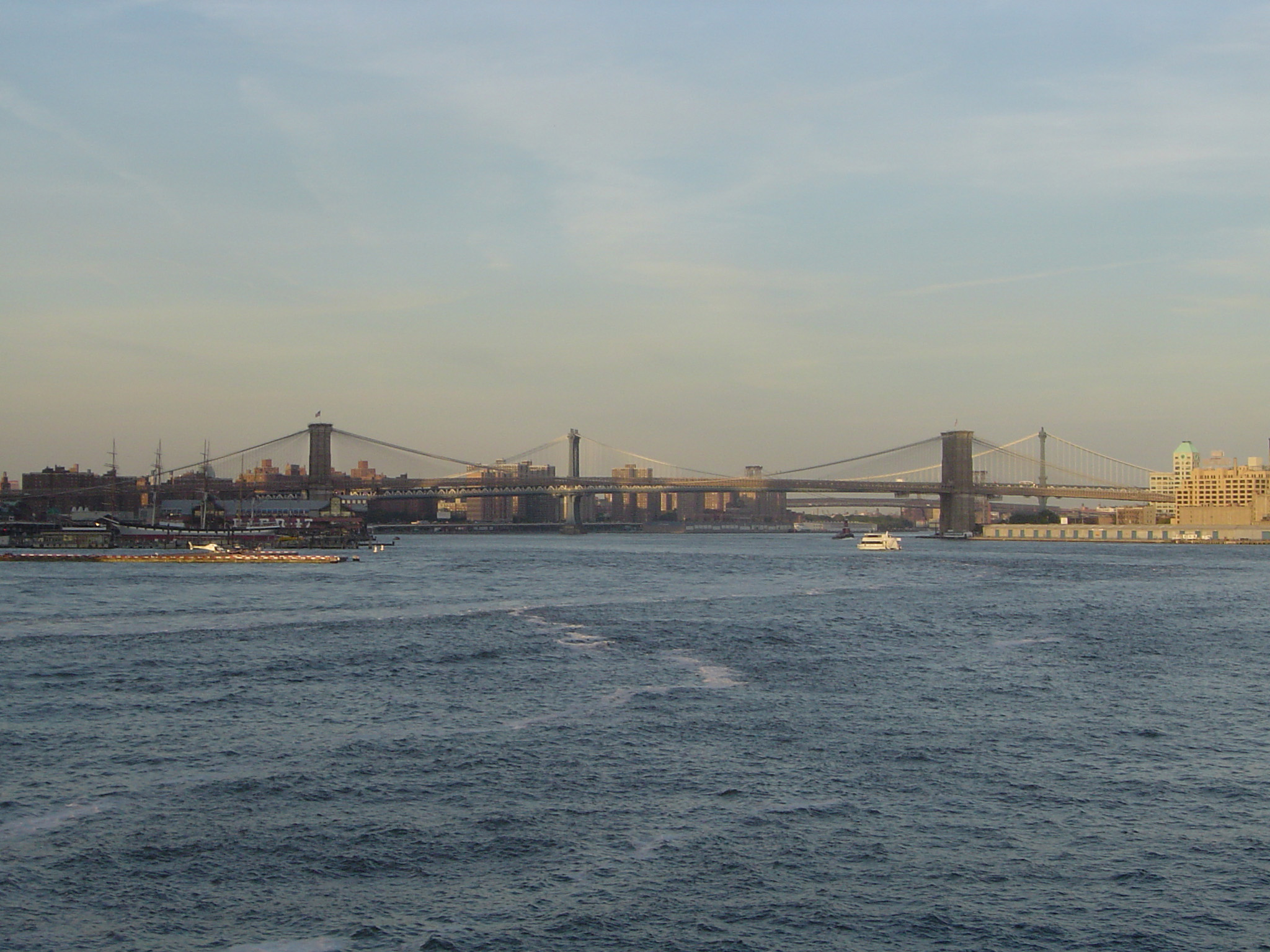 an image of View across the water of the steel structure of Brooklyn Bridge, New York, a popular tourist attraction and landmark