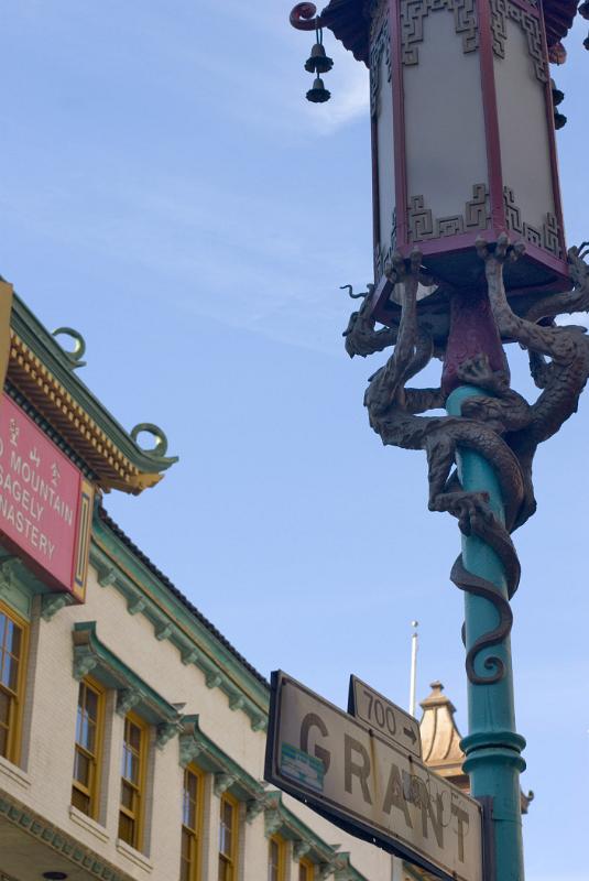 Artistic Details of Decorated Street Post In Front a Vintage Building in China Town. Captured on Lighter Blue Sky Background.