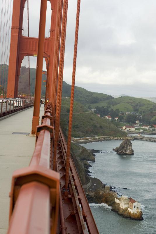 Walk along the Golden Gate Bridge Walk along the Golden Gate Bridge on the pedestrian footpath with a view along the red painted railing with the rocks and bay below