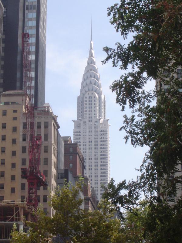 View of the exterior facade pf the Chrysler Building, Manhattan, New York , past green foliage