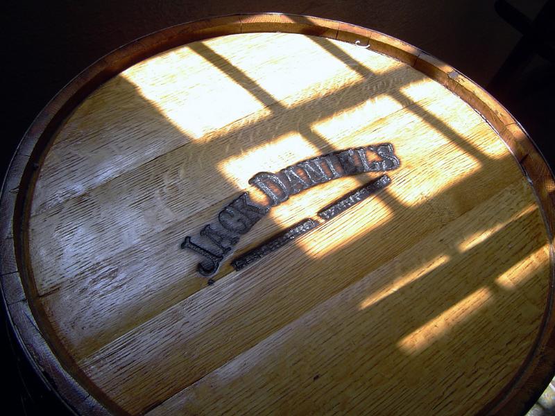 Jack Daniel whiskey barrel for maturing and ageing their whiskey in a cellar with sunlight from a window on the wooden oak surface