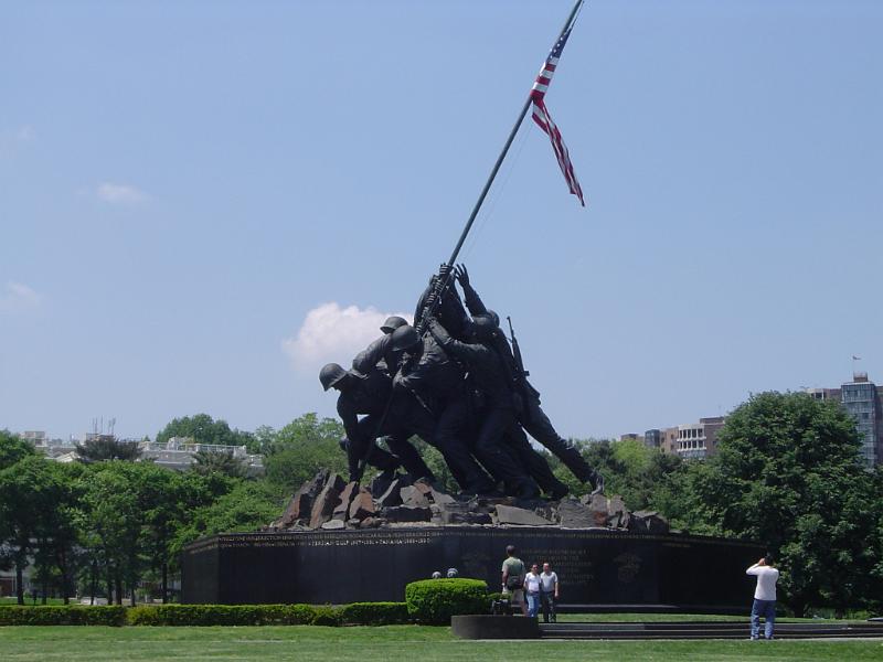 Historic War Memorial Statue of Marine Corps Historic Black War Memorial Statue of Marine Corps with American Flag on Huge Platform. Isolated on Light Blue Gray Sky Background.