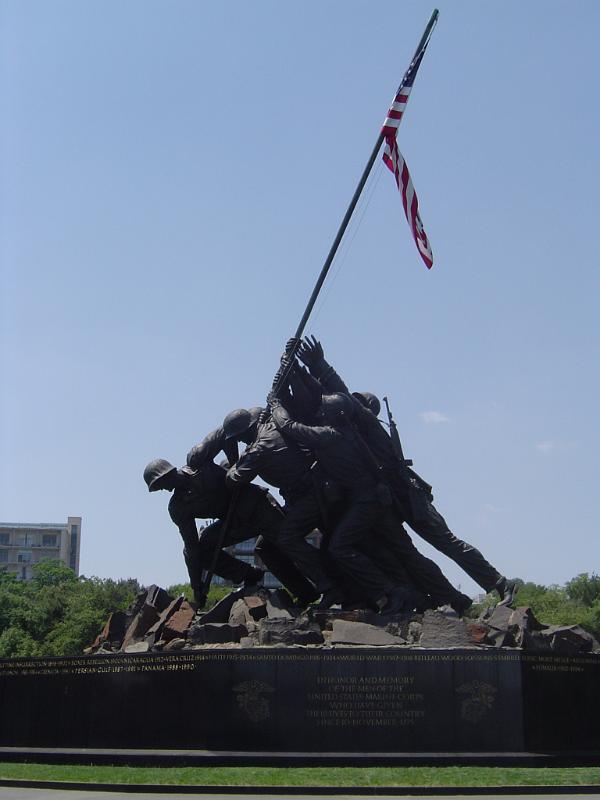 Marine Corps War Memorial Statue with Flag Old Vintage Marine Corps War Memorial Statue Holding American Flag. Isolated on Light Blue Gray Sky Background.