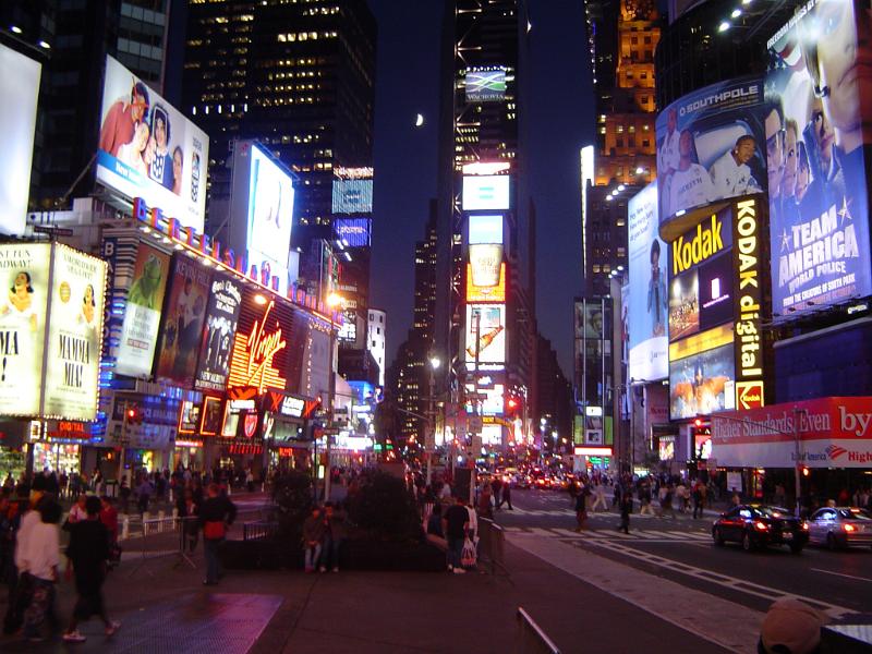 Busy night street scene in Times Square Busy night street scene in Times Square, New York with brightly colored neon signs and pedestrians and shoppers