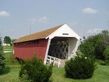 Covered Bridge with Green Grasses and Plants on Sides at Madison County Iowa. Isolated on Light Blue Sky Background.