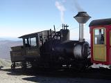 Close up Old Vintage Steam Locomotive Passing on Cog Railway. Isolated on Light Blue Sky Background.