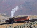 Vintage Steam Locomotive Passing Cog Railway on Rocky Landscape. Captured with Mountains Background.