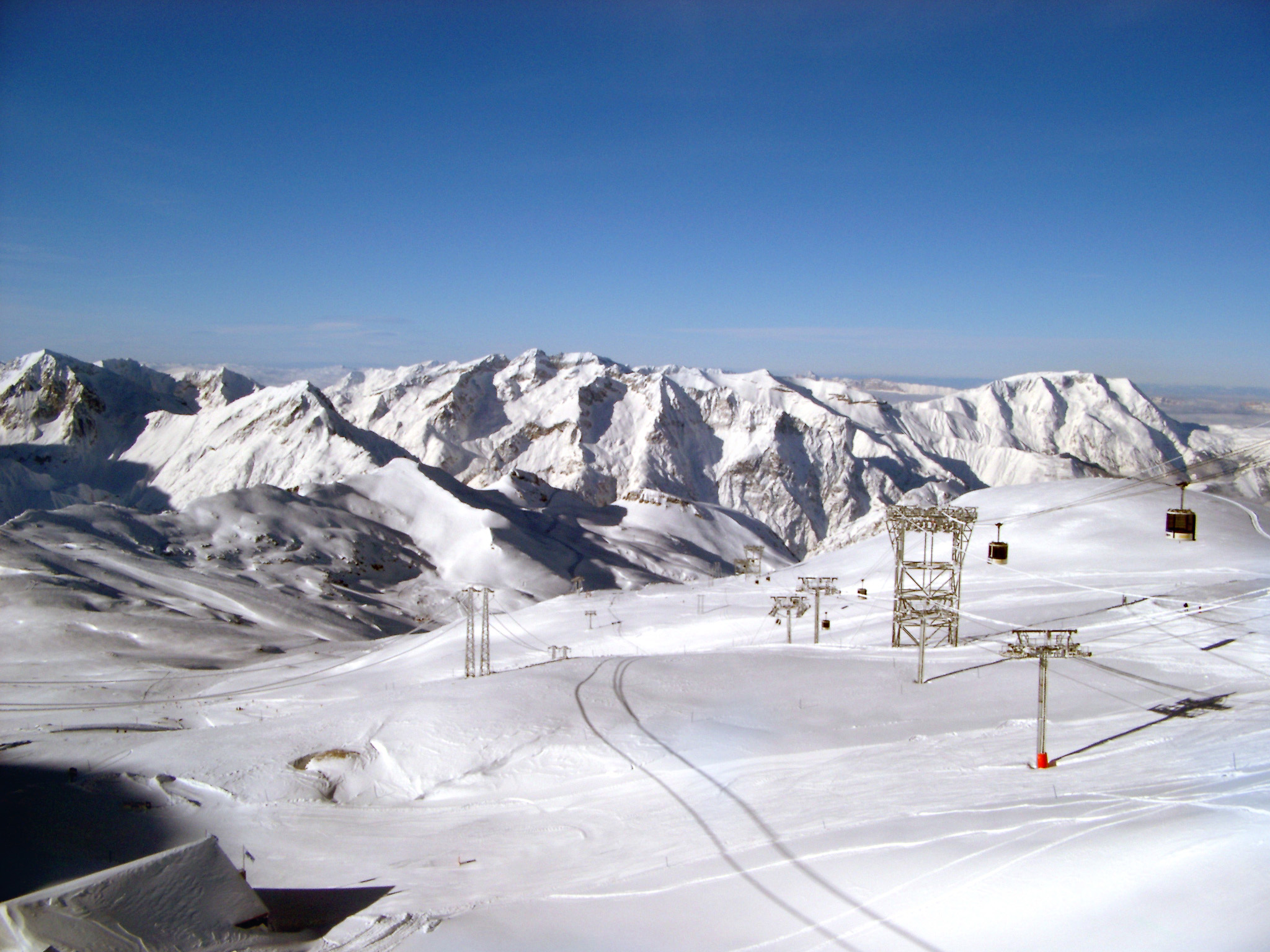 an image of Scenic winter landscape with snow covered mountains and a piste with chair lifts for skiers