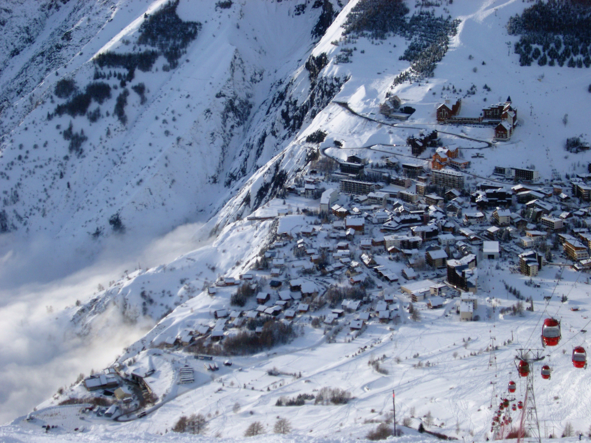 an image of Winter holiday in an alpine village with an aerial view of buildings scattered on a snow covered mountain slope