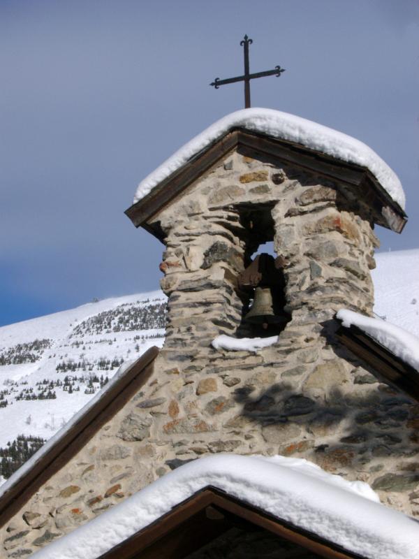 Historic Alpine Church, Covered with Snow, with Vintage Bells and Cross