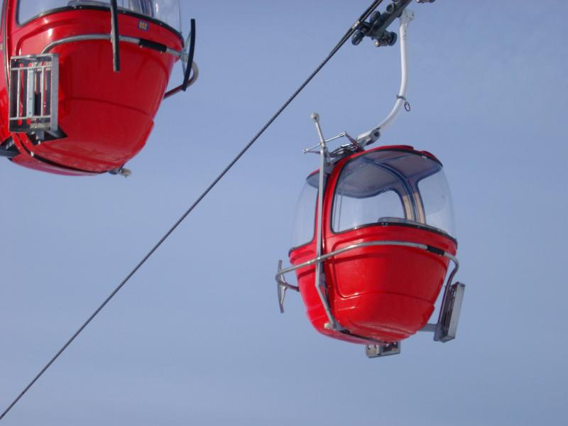 High-Tech Empty Red Cable Cars for Adventure on Lighter Blue Sky Background.