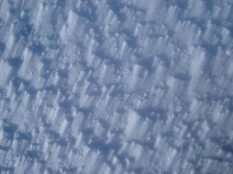 Textured Wind Blown Ice Snow on Ground During Winter Holiday Season.