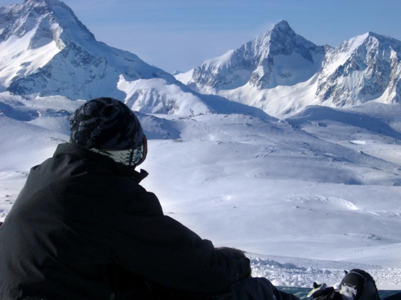 Young snowboarder enjoying a day on the snow Young snowboarder enjoying a day on the snow during a winter vacation to the Alps with snow covered peaks in the background