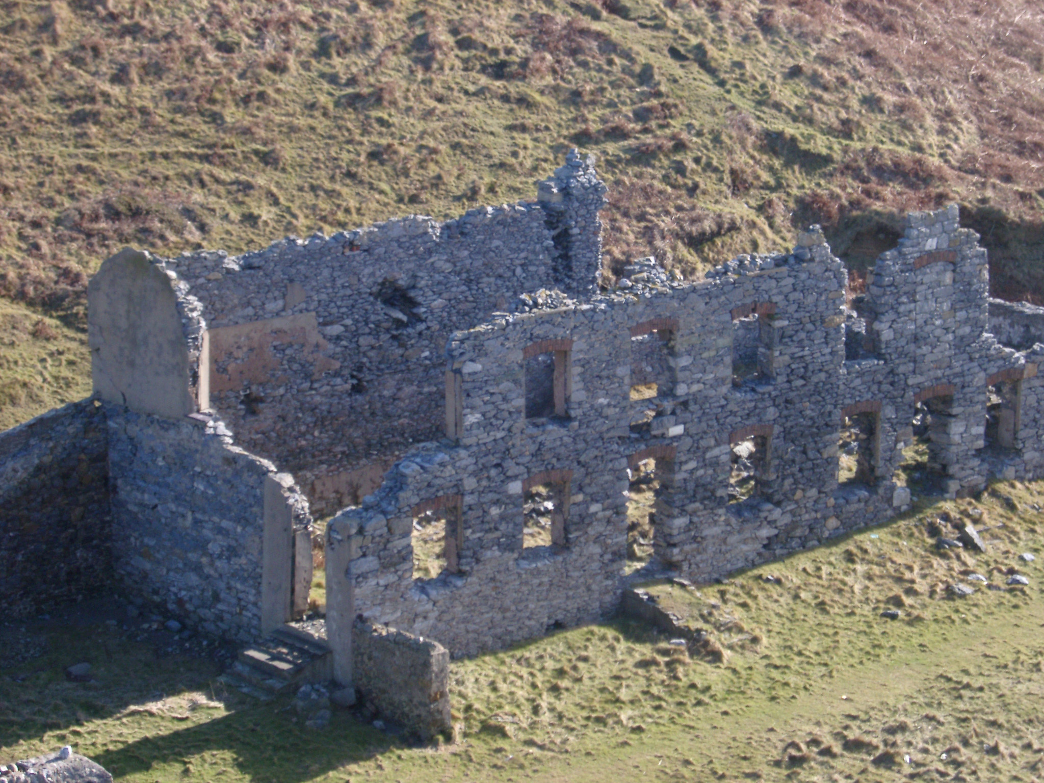 an image of Ruins of an old factory with just the remnants of the stone exterior walls with window and door openings still standing viewed from a high angle