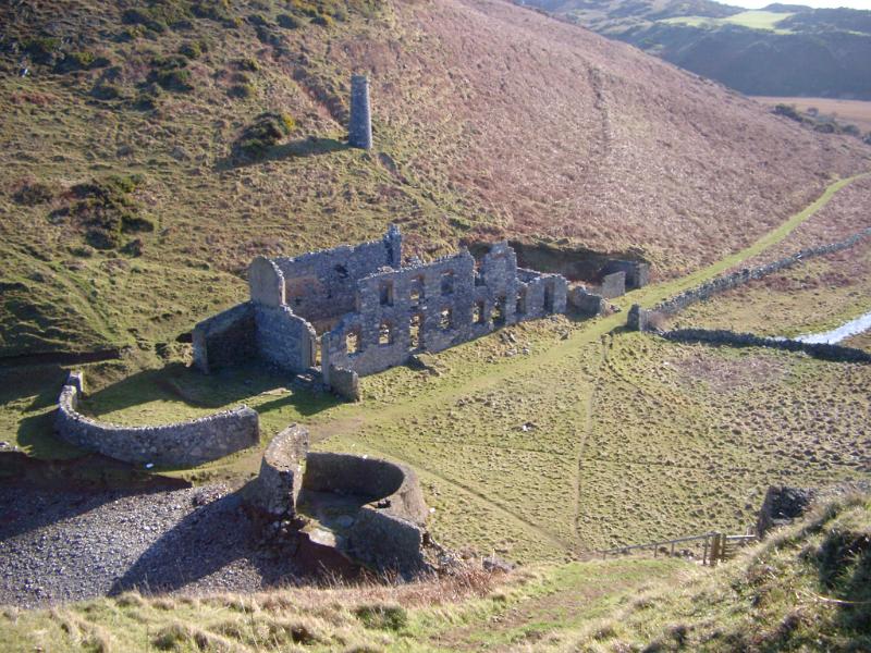 Old stone factory ruins in a mountain valley with an old iron smelter and chimney, view from above