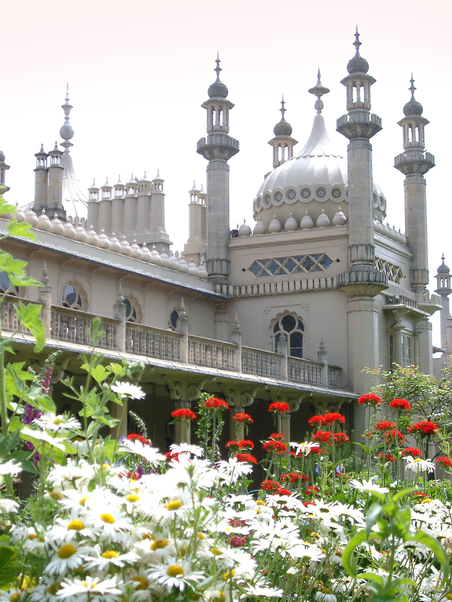 an image of Onion dome and minarets of the Brighton Royal Pavilion viewed across a bed of summer flowers with white daisies in the foreground