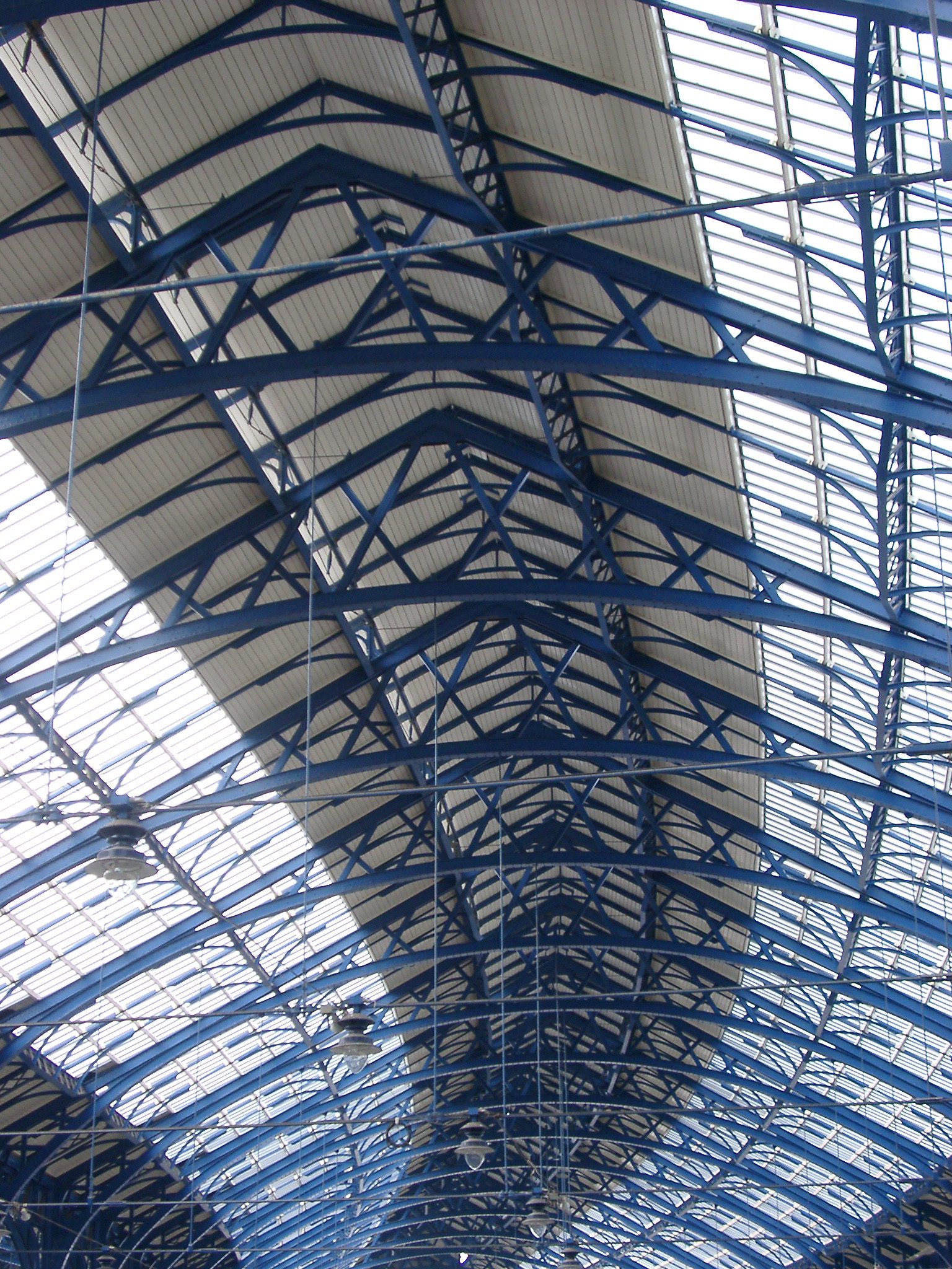an image of Looking Up at Blue Girder and Glass Ceiling in Brighton Railway Station, Brighton, England