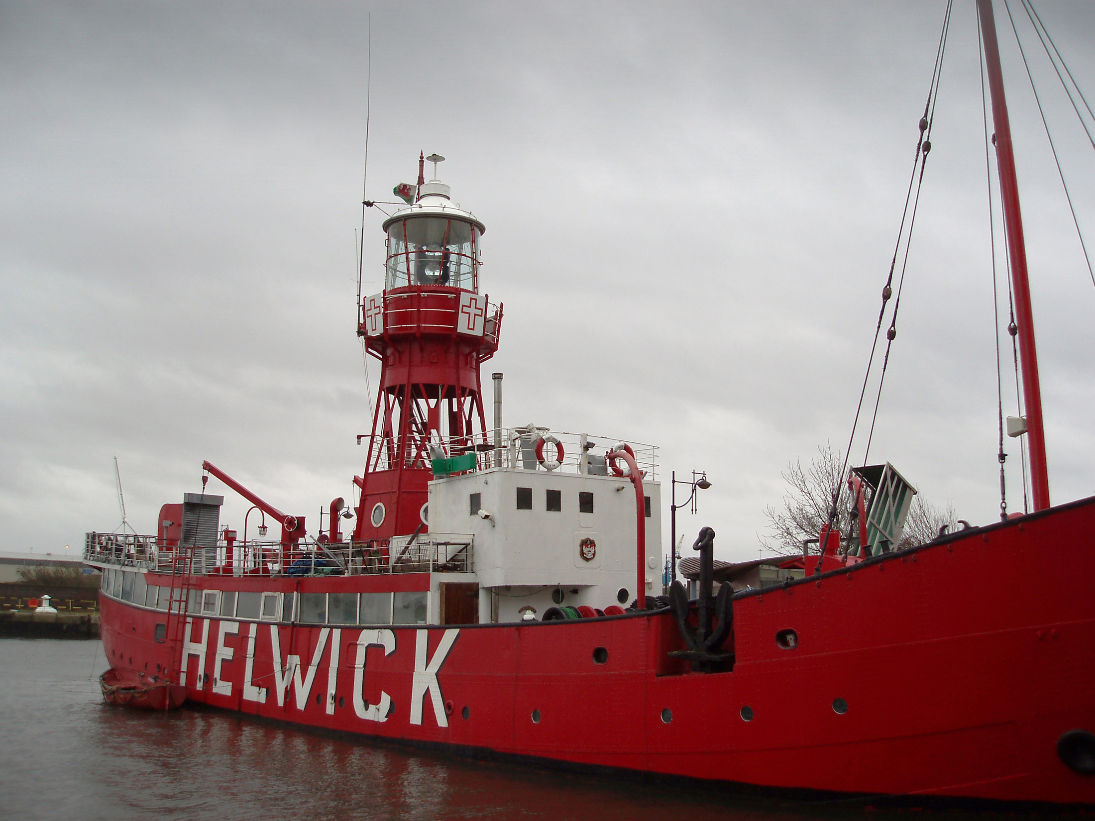 an image of Historical Red Helwick Lightship at the Dock of Cardiff Bay, Wales. Captured on a Gray Sky Background.