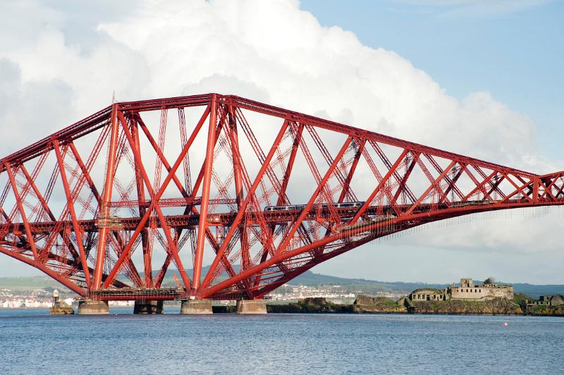 a train dwarfed by the giant structure of the forth bridge, firth of forth, scotland