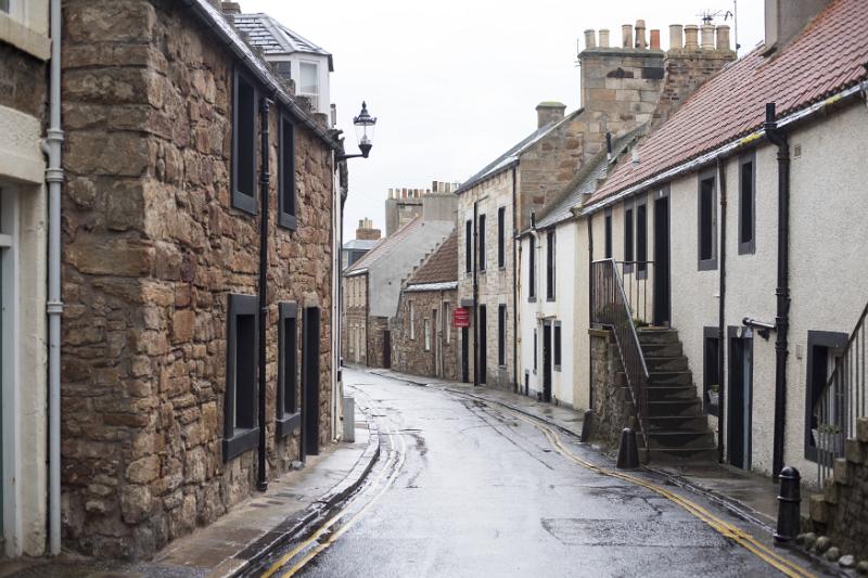 Narrow street in Cellardyke, Scotland lined with quaint cottages on a rainy overcast day