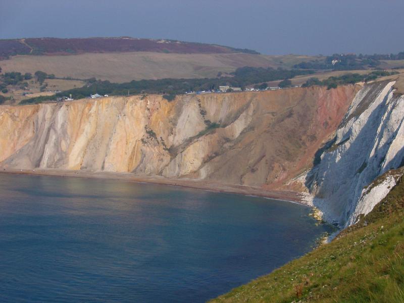 View along the scenic coastline of the Alum Bay cliffs, Isle of Wight showing erosion of color of the chalk with a calm ocean below