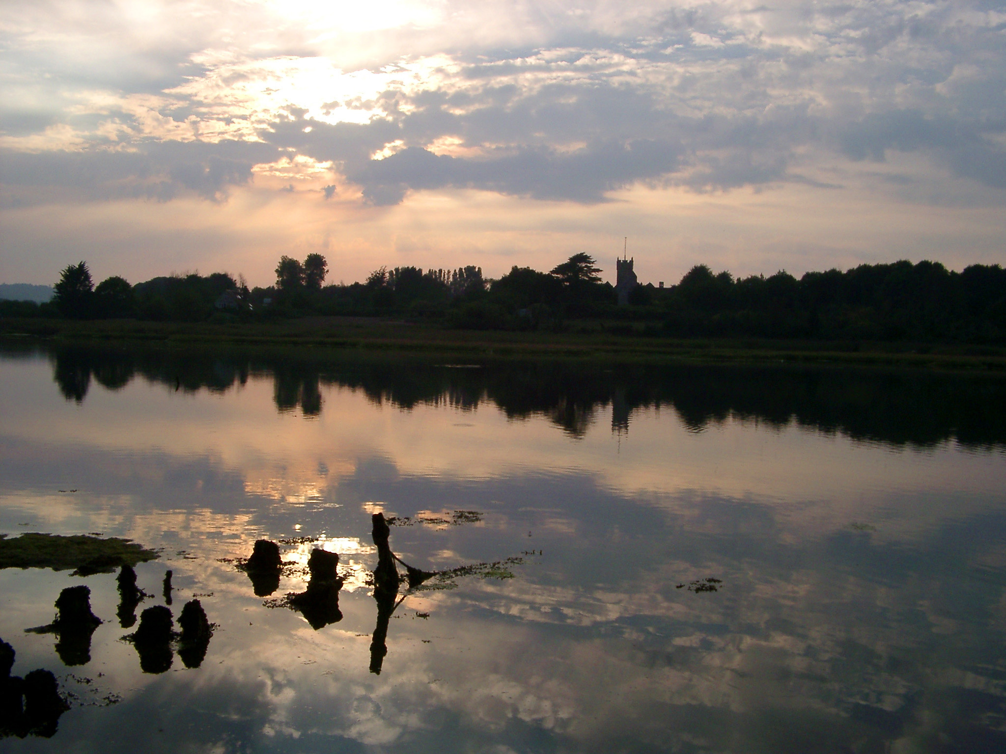 an image of River Yar near Freshwater at sunset with the trees and a church reflected in the calm water