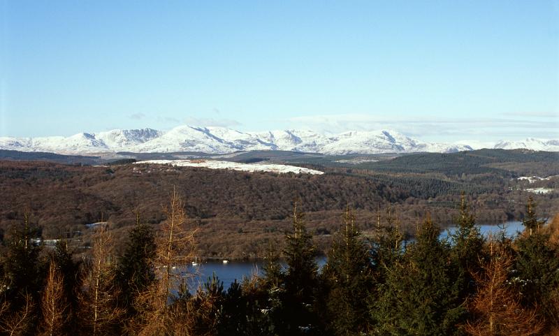 panoramic view of the hills around lake windermere with peaks capped by winter snow