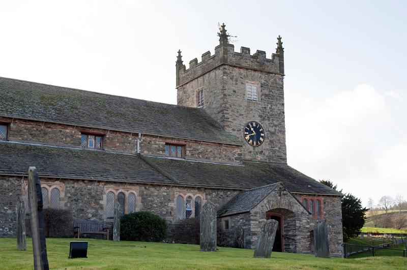 Graveyard and view of St Michael and All Angels church in Hawkshead, the most popular village for tourists in the Lake District in Cumbria