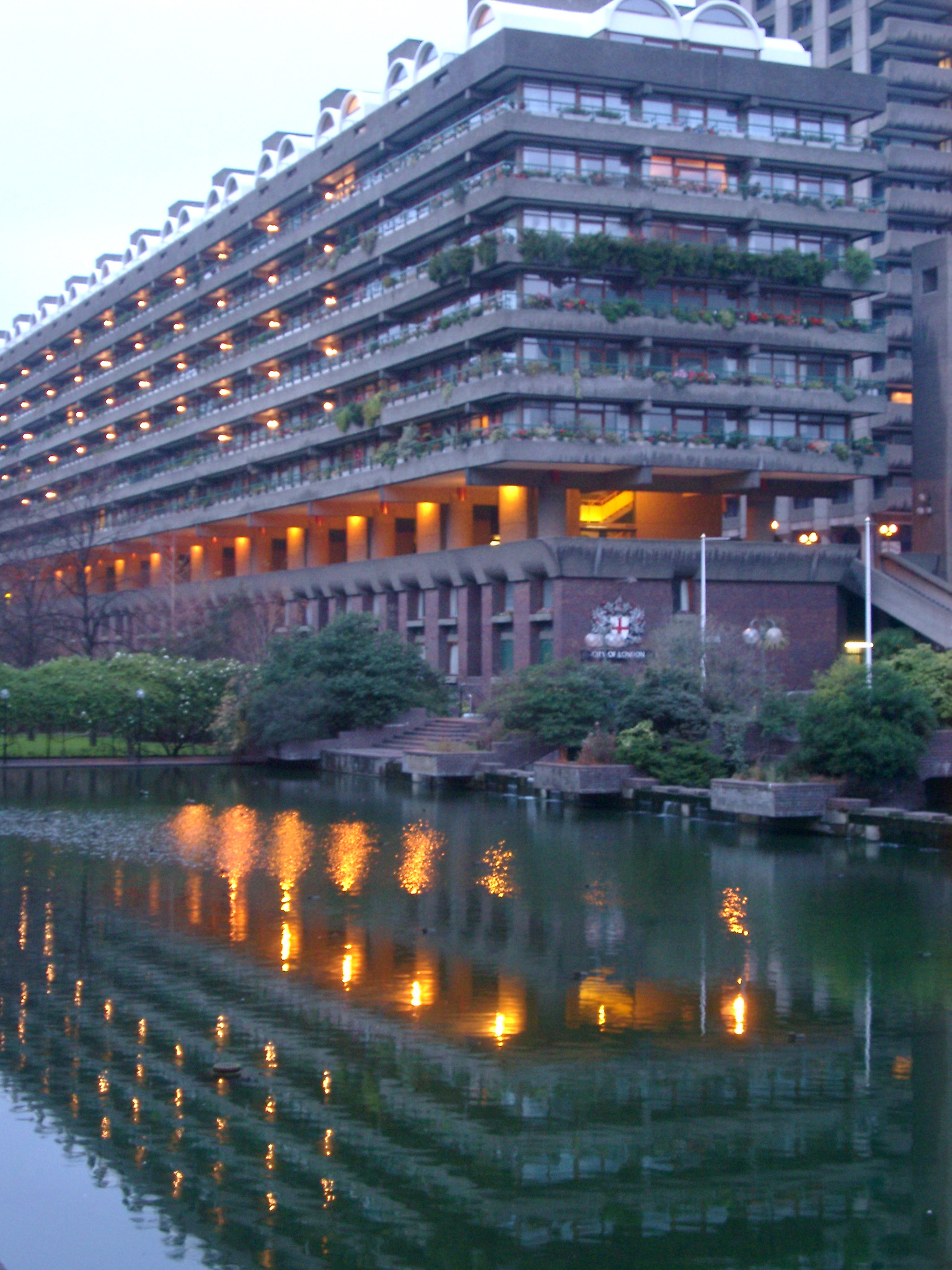 an image of Barbican apartment block at dusk with the lights reflected in a pool below, London, England