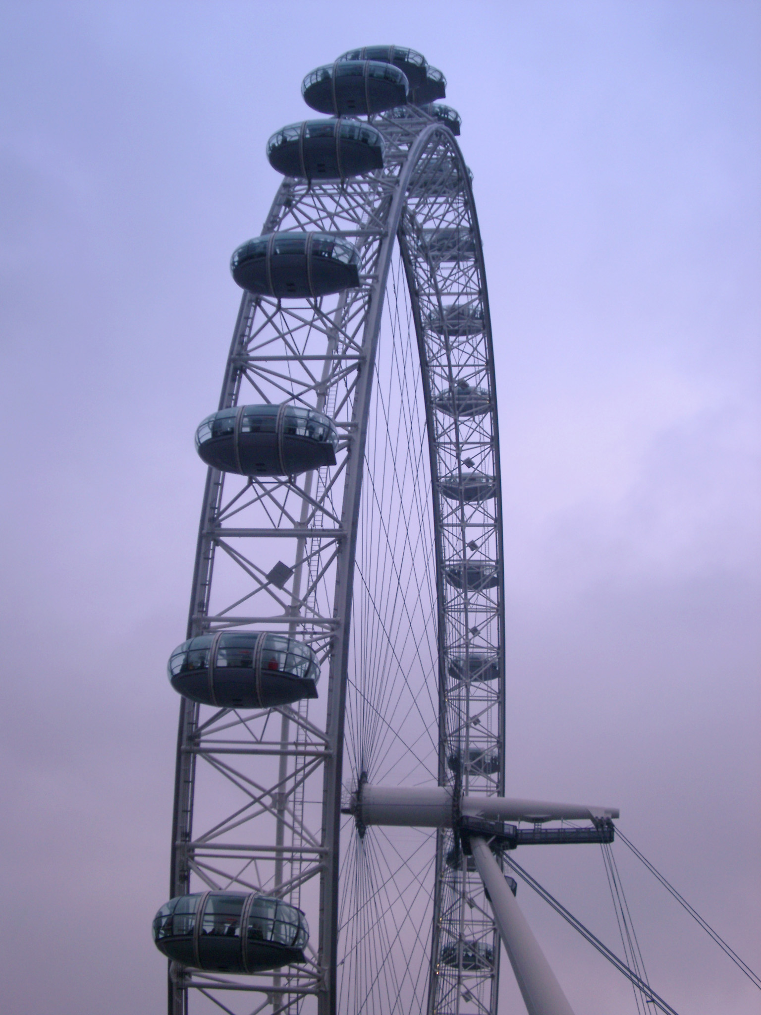 an image of View of the rim of the The London Eye ferris wheel on the bank of the Thames River, London with its ovoid viewing capsules popular with tourists silhouetted against an evening sky