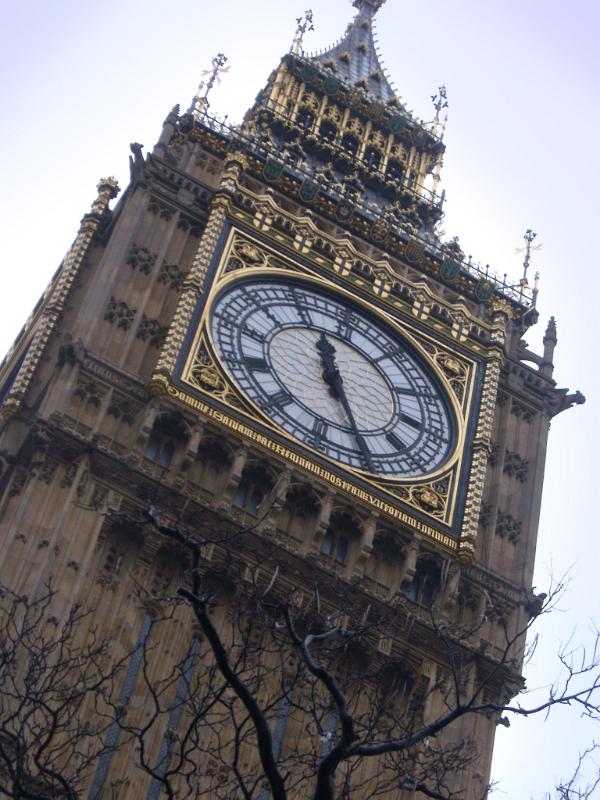 detail of the dial of one of the clocks and the ornate Gothic stone facade of the Clock tower on the Palace of Westminter, London