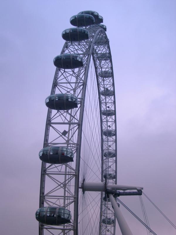 View of the rim of the The London Eye ferris wheel on the bank of the Thames River, London with its ovoid viewing capsules popular with tourists silhouetted against an evening sky