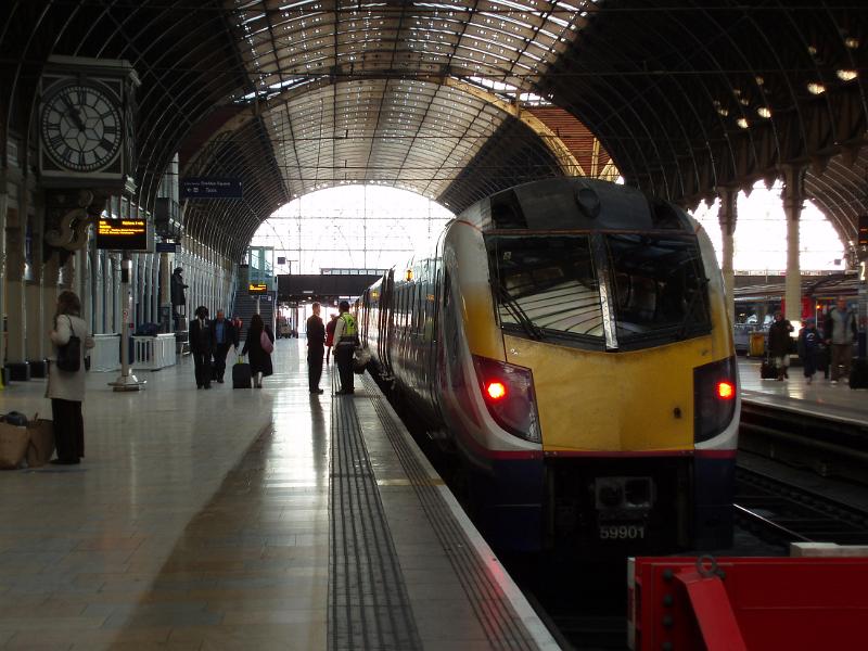 Train at the platform in Paddington Station London with commuters standing chatting and waiting for their transport, interior view under the arched roof