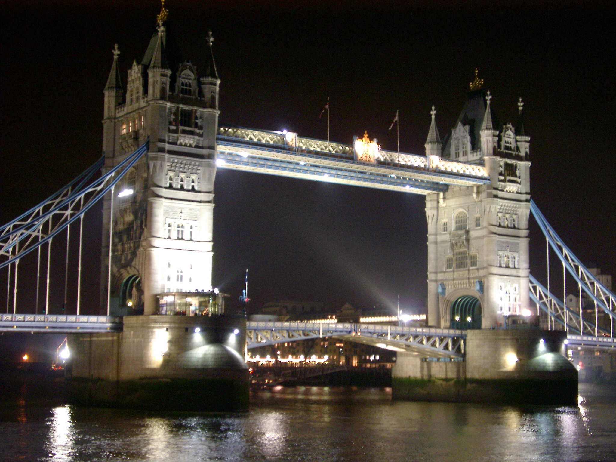 an image of Tower Bridge, London, on the River Thames illuminated at night with the drawbridge down and reflections on the calm water