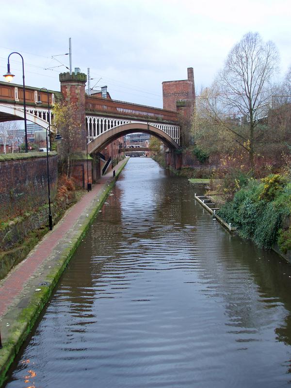 Manchester canal towpath leading under the old arched red brick railroad to the industrial warehouses now part of the Castlefield conservation area