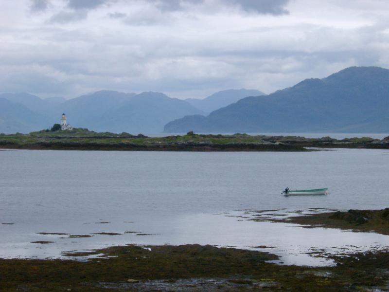 Imposing mountains on the Isle of Skye Imposing mountains on the Isle of Skye viewed across water with a lighthouse and small rowboat in the foreground