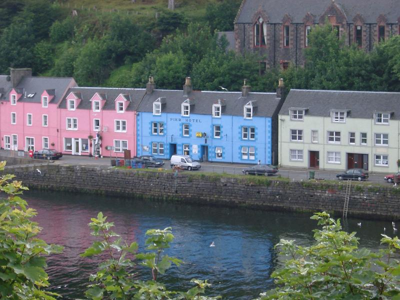 Row of colorful fishermans houses on a terrace in Portree, Isle of Skye, painted pink, cyan and white
