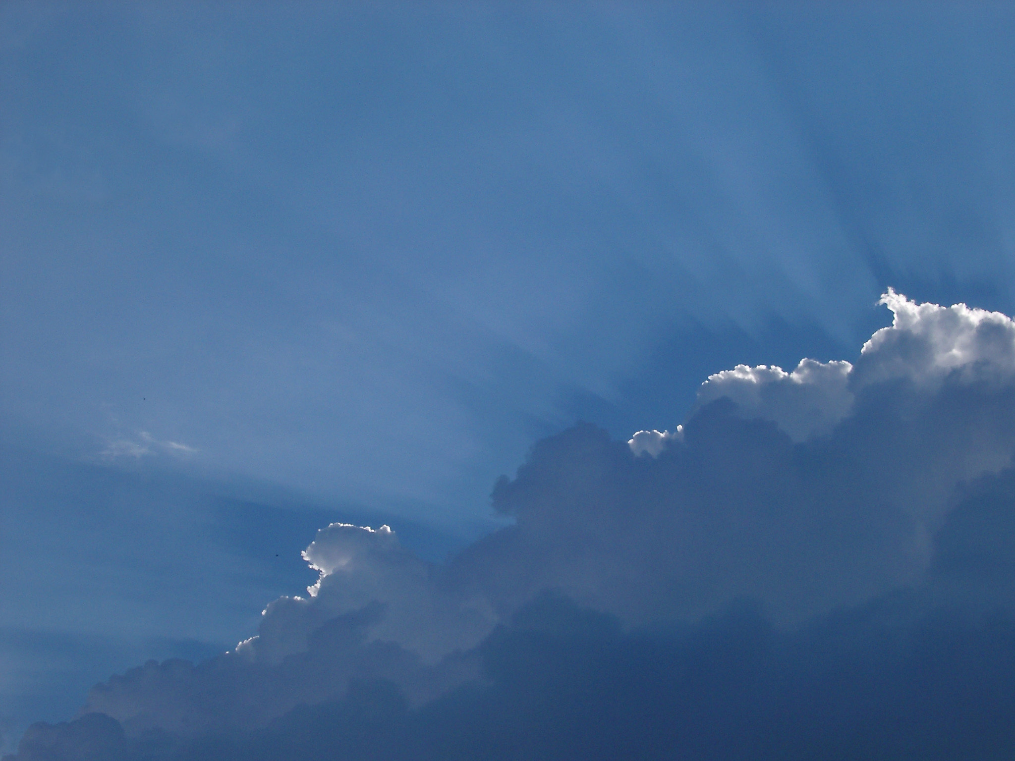 an image of Backlit clouds in a blue sky with the suns rays just gilding the top of the formation in a nature and environmental background