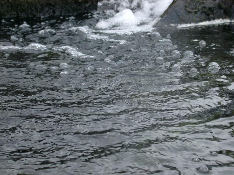 Bubbling water in a fast flowing stream in a full frame background texture