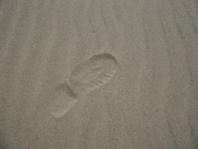Single human footprint on the sand Close up shot of conceptual single human footprint on the gray sand at the beach.