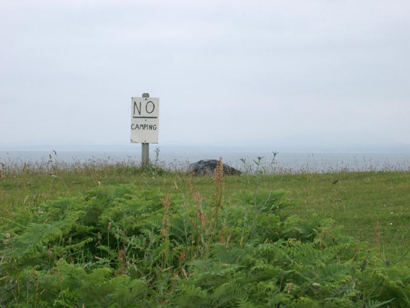 No Camping sign Private hand written rustic wooden No Camping sign on an open plot of grassy land on a misty day