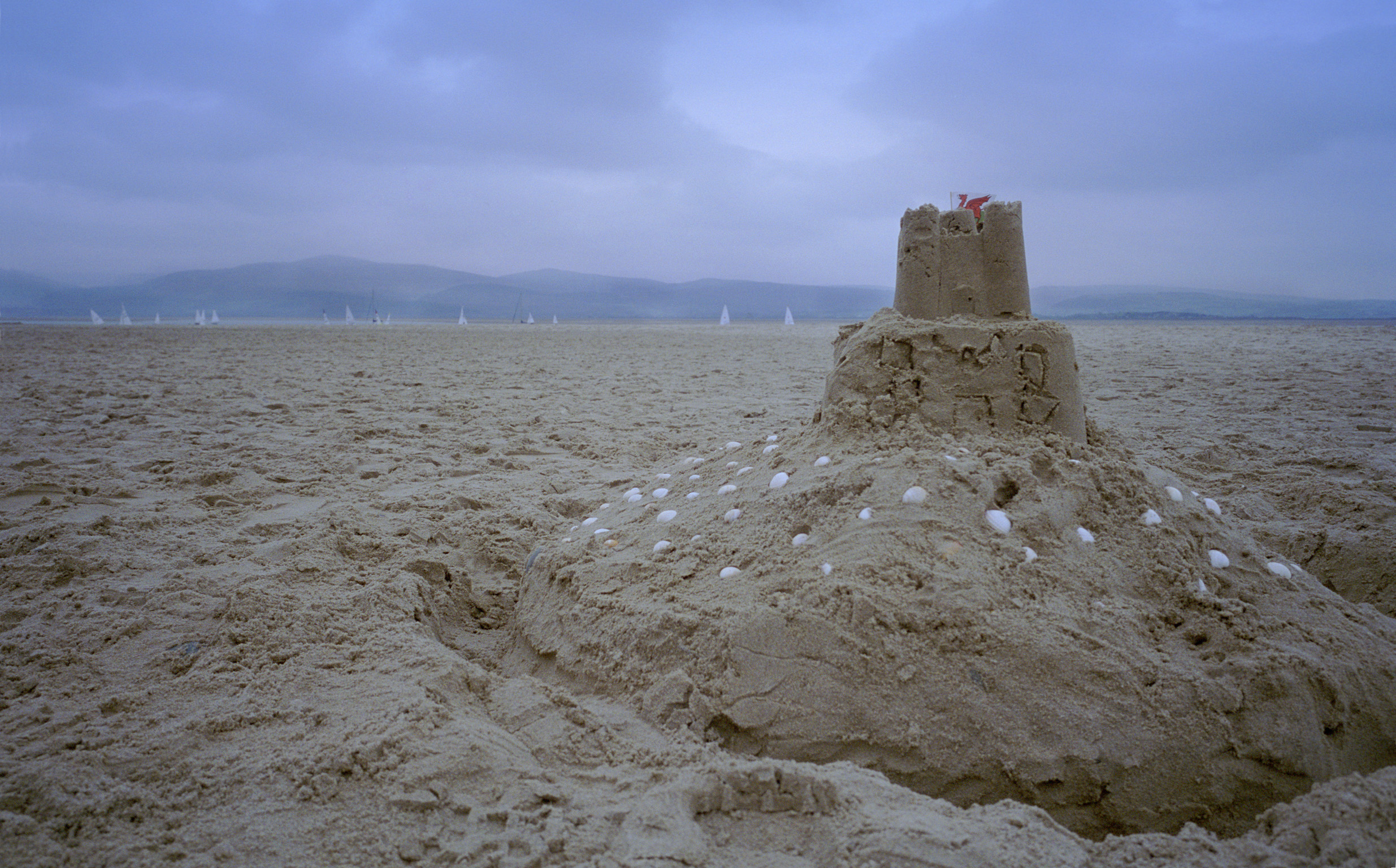 an image of Close Up of Sand Castle on Empty Beach with Dark Overcast Clouds