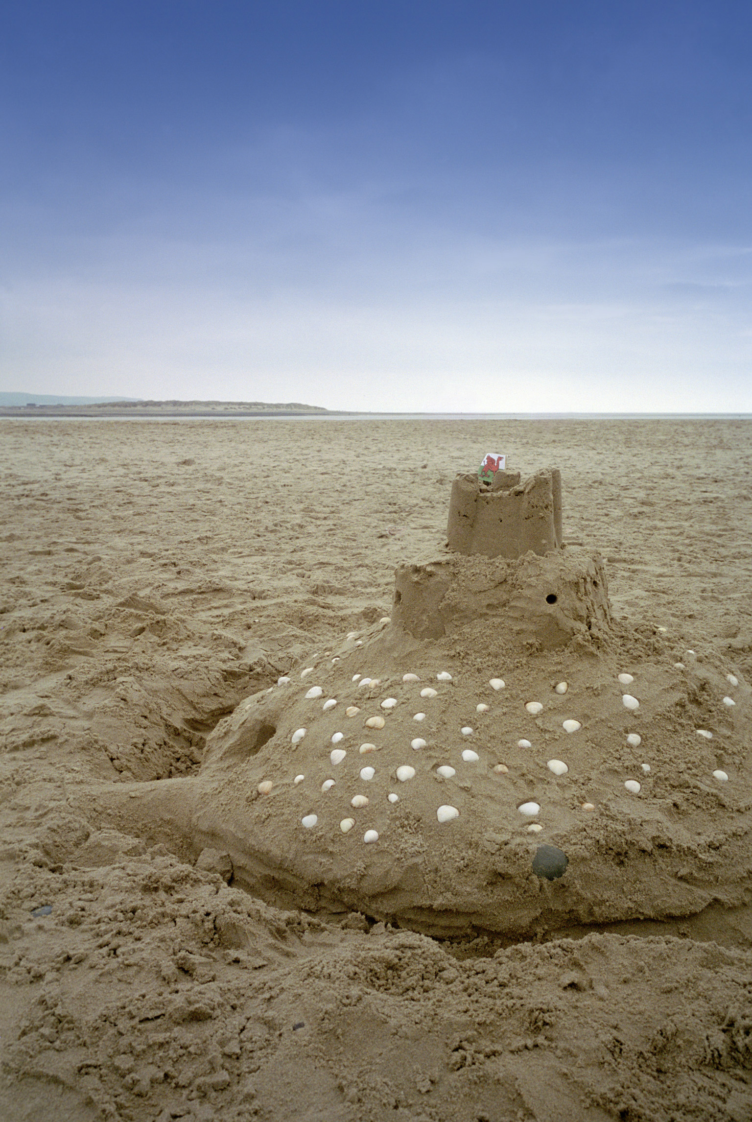 an image of Sandcastle decorated with shells on a beach at the seaside with golden beach sand a reminder of as happy afternoon spent playing in the sand